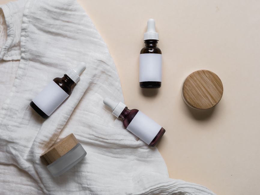 Elegant glass skincare bottles with labels on a textured fabric, perfect for cosmetic branding and product display.